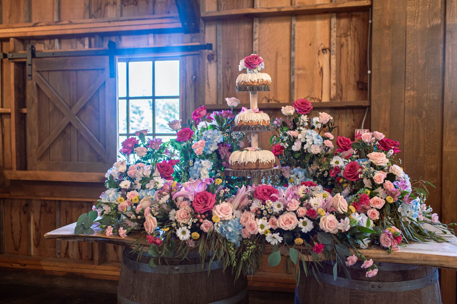 A cake table overflowing with garden roses, hydrangea, lilies and daisies