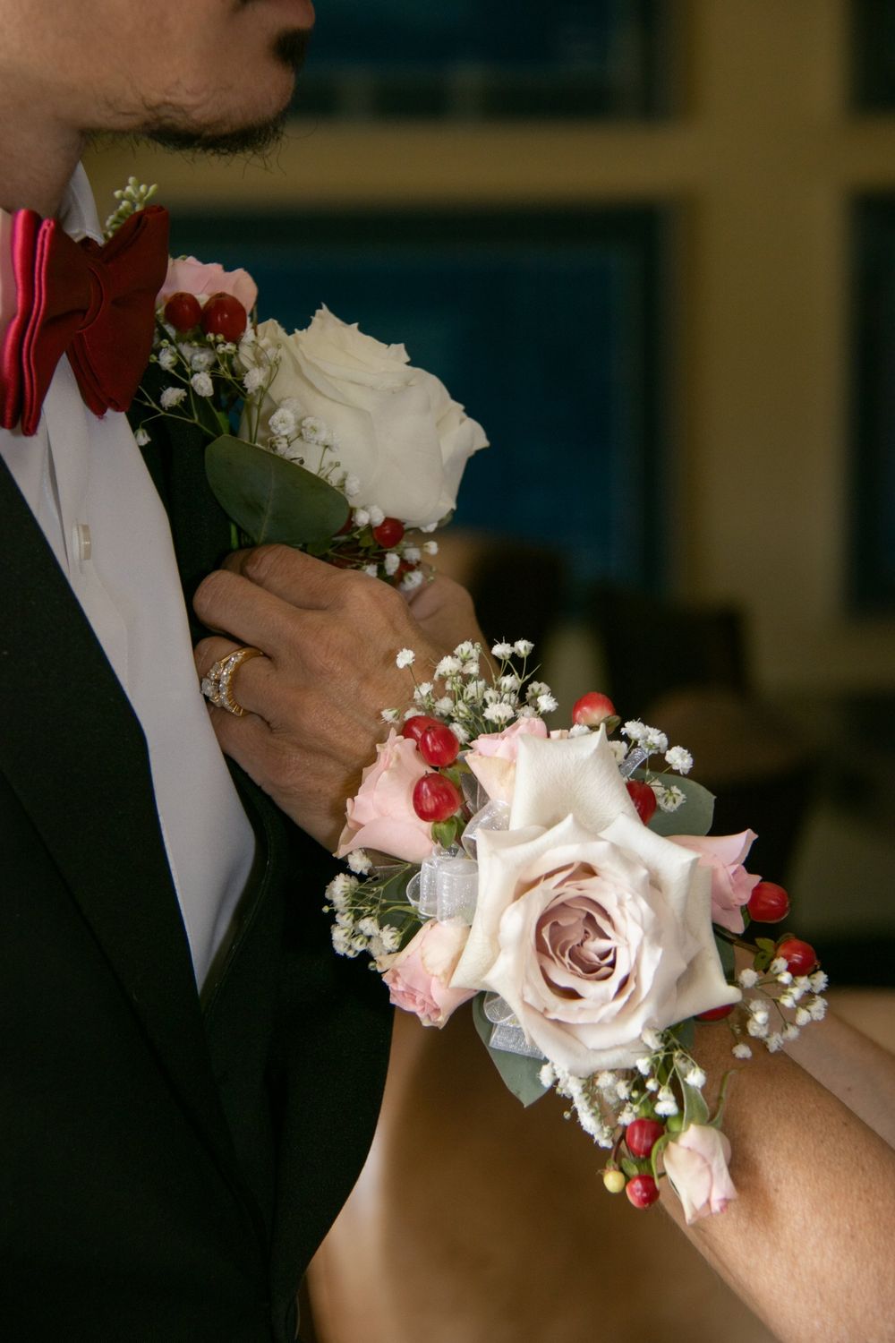 A boutonniere and a wrist corsage of roses and hypericum