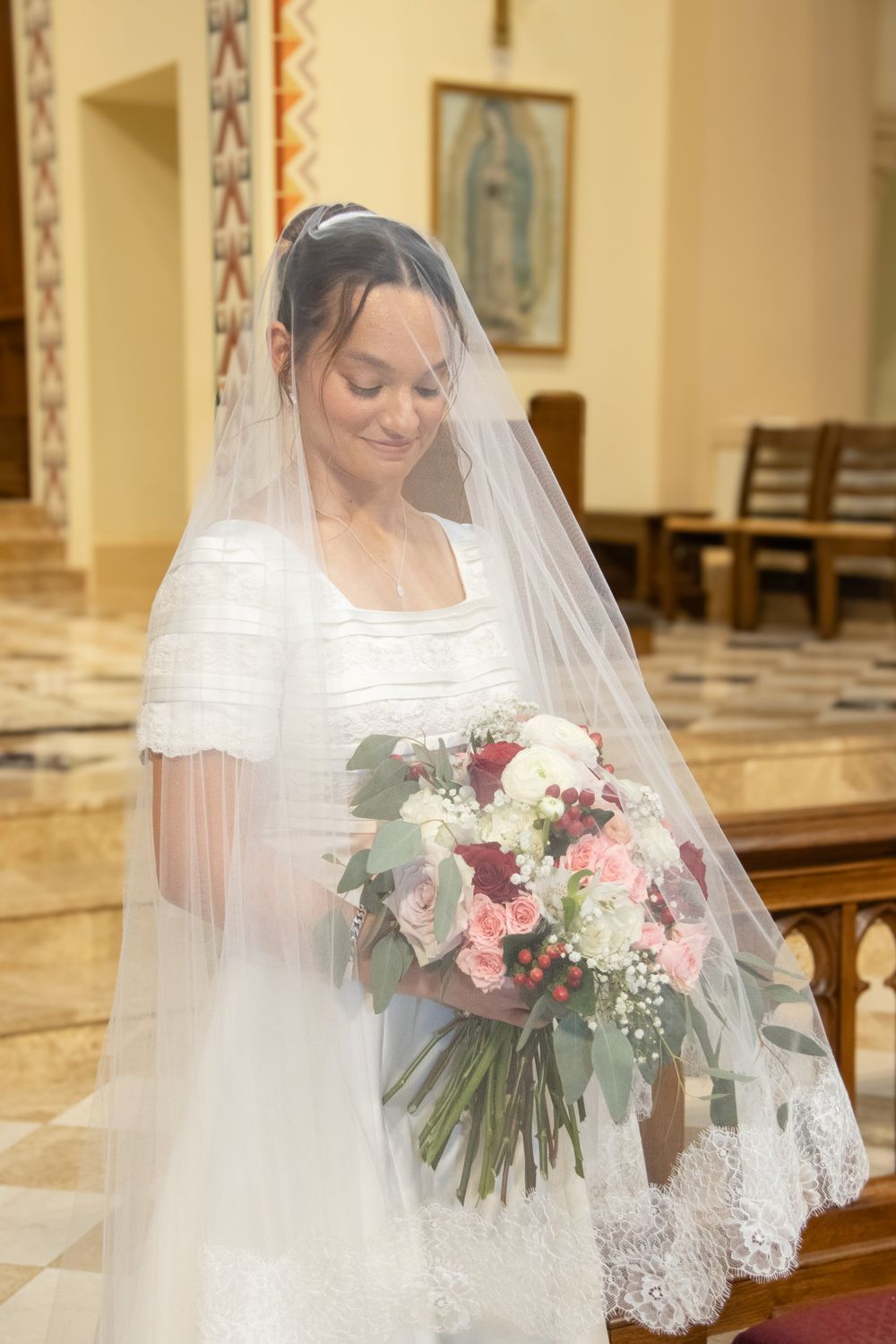 A bride with her bouquet of blush and red roses