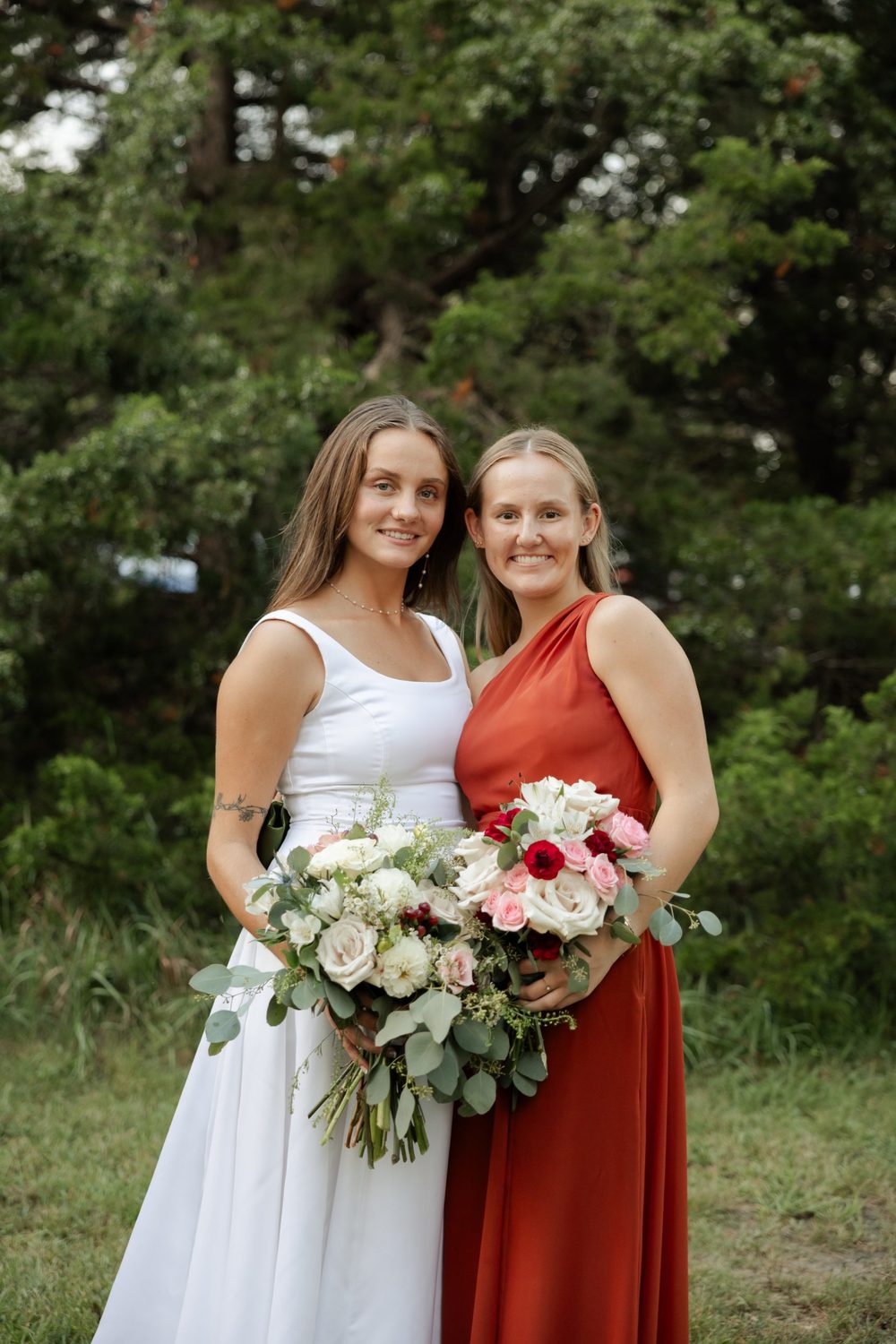 A bridesmaid’s bouquet of blush and pink roses with red carnations