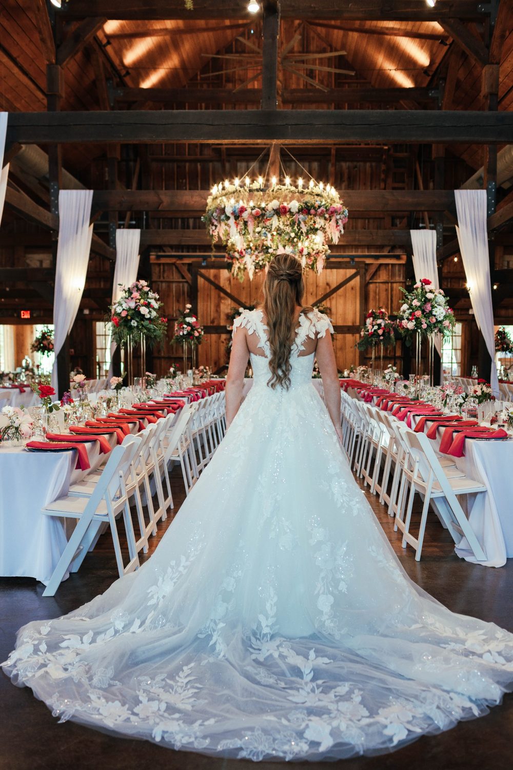 A bright floral chandelier hung from the ceiling over a reception of tall, colorful centerpieces