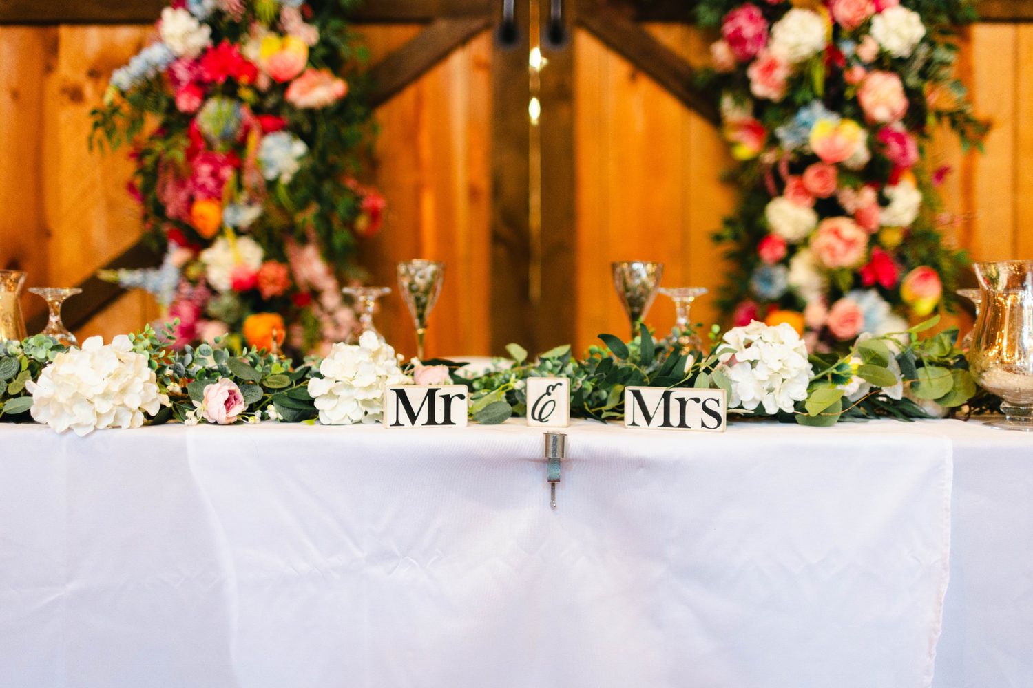 A garland of hydrangea and greenery on the head table, before a floral backdrop