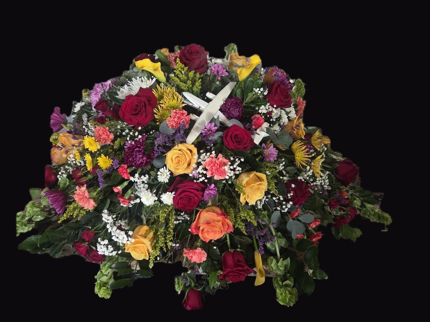 A casket spray of roses, lilies and carnations with a model airplane at its center, honoring an aircraft engineer