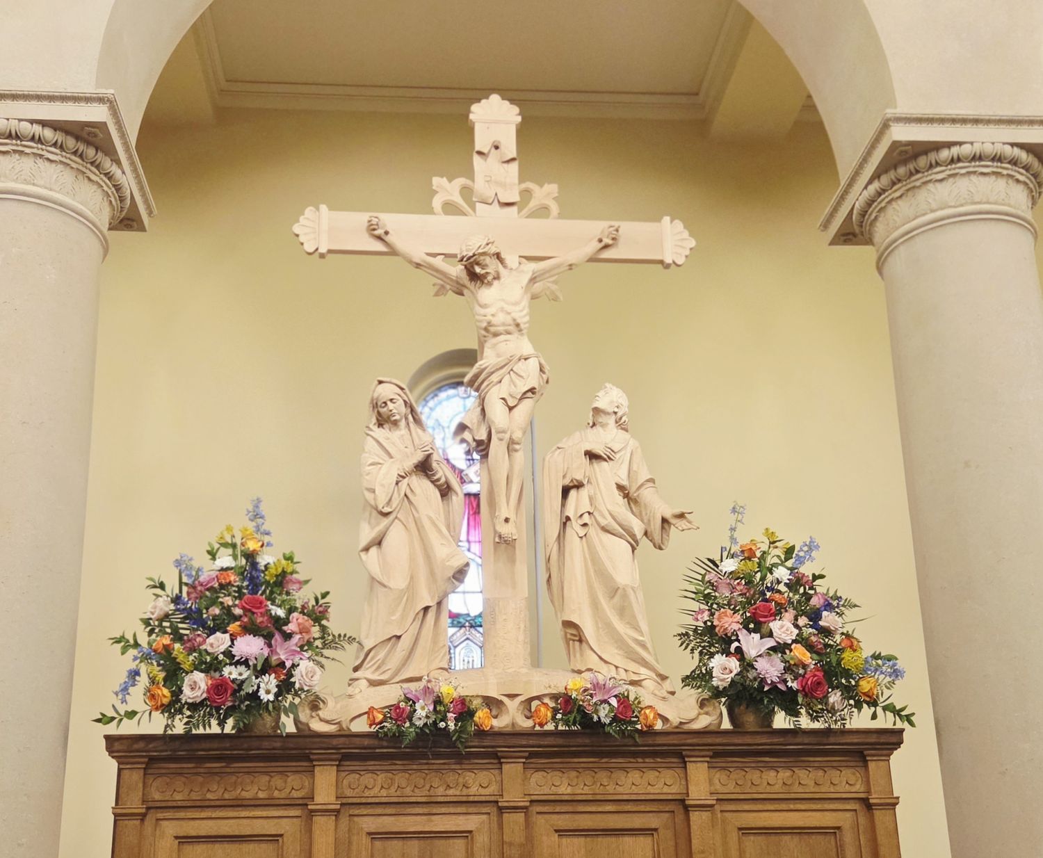 Altar arrangements in spring colors beneath the crucifix