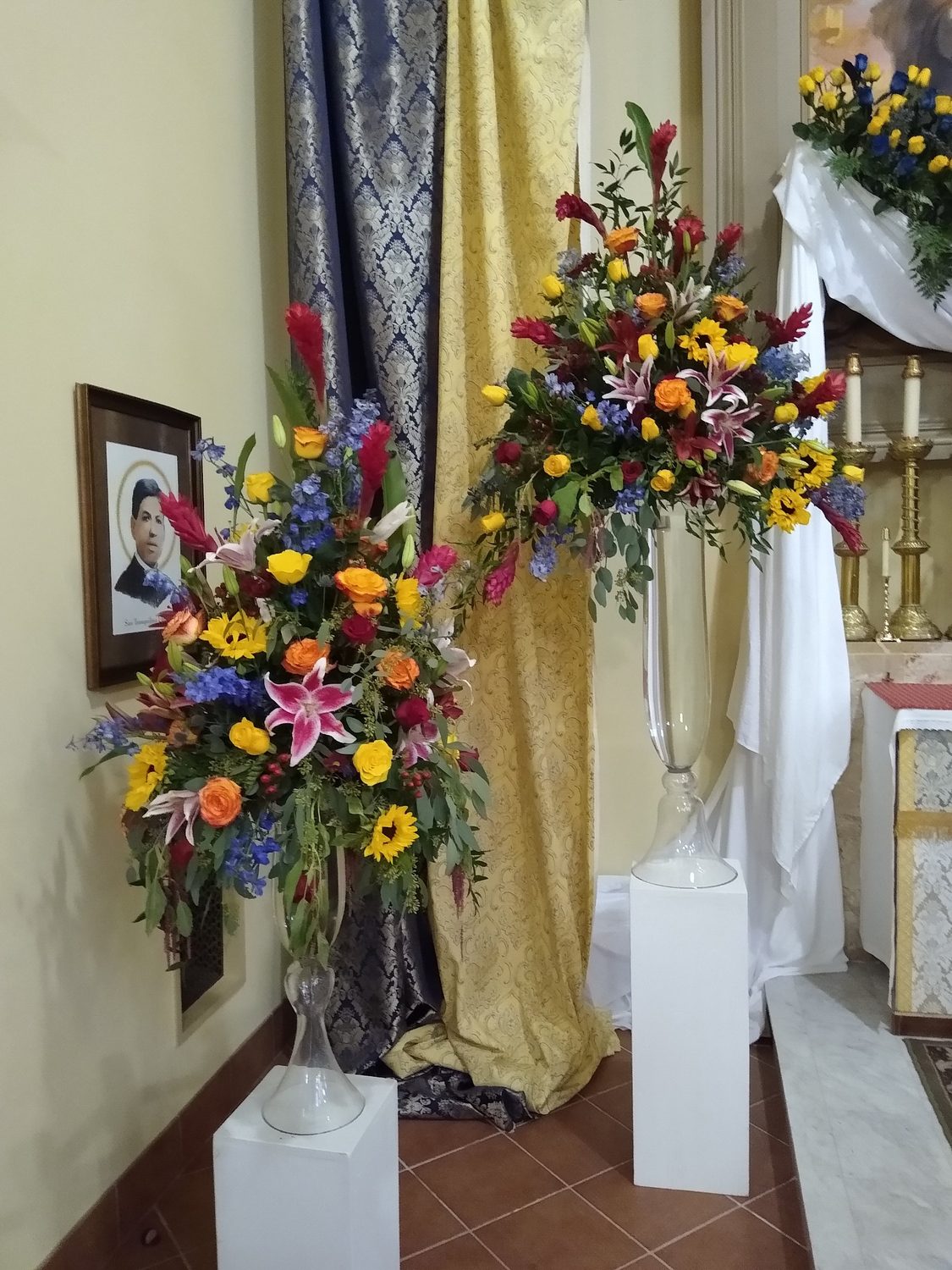 Twin pedestal arrangements of red ginger, stargazer lilies, sunflowers and roses in the sanctuary