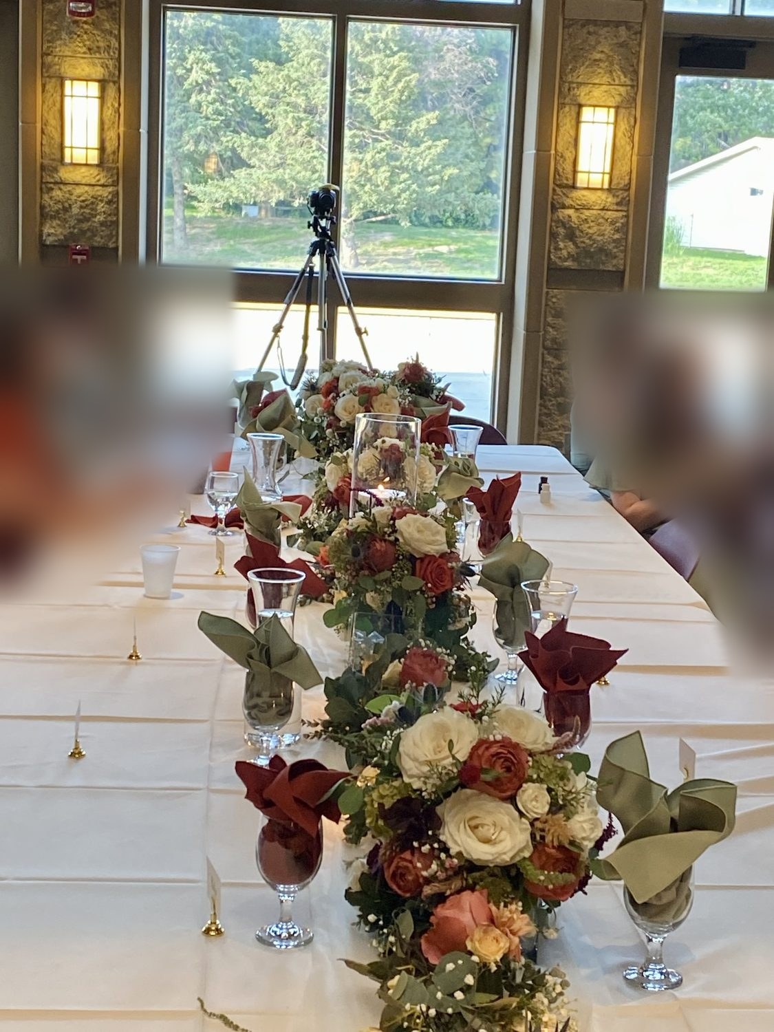 A long floral runner of ivory and rust roses with a floating candle on the head table