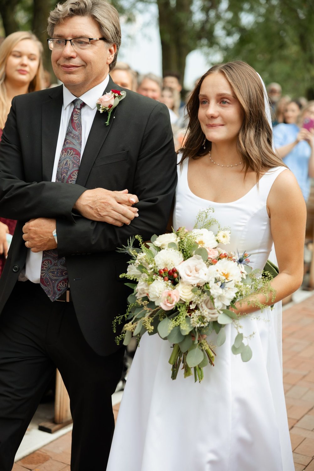 Walking down the aisle with a bouquet of blush roses, dahlias, thistle and hypericum