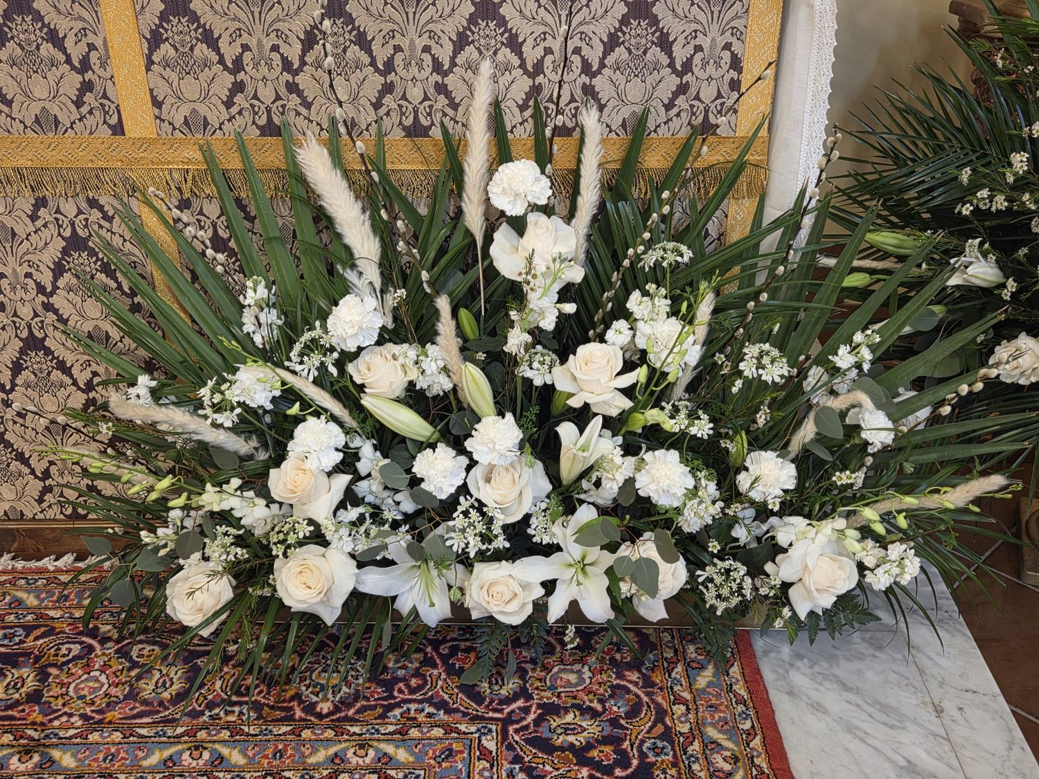 White roses, lilies, carnations and pampas fanned with palm before the altar