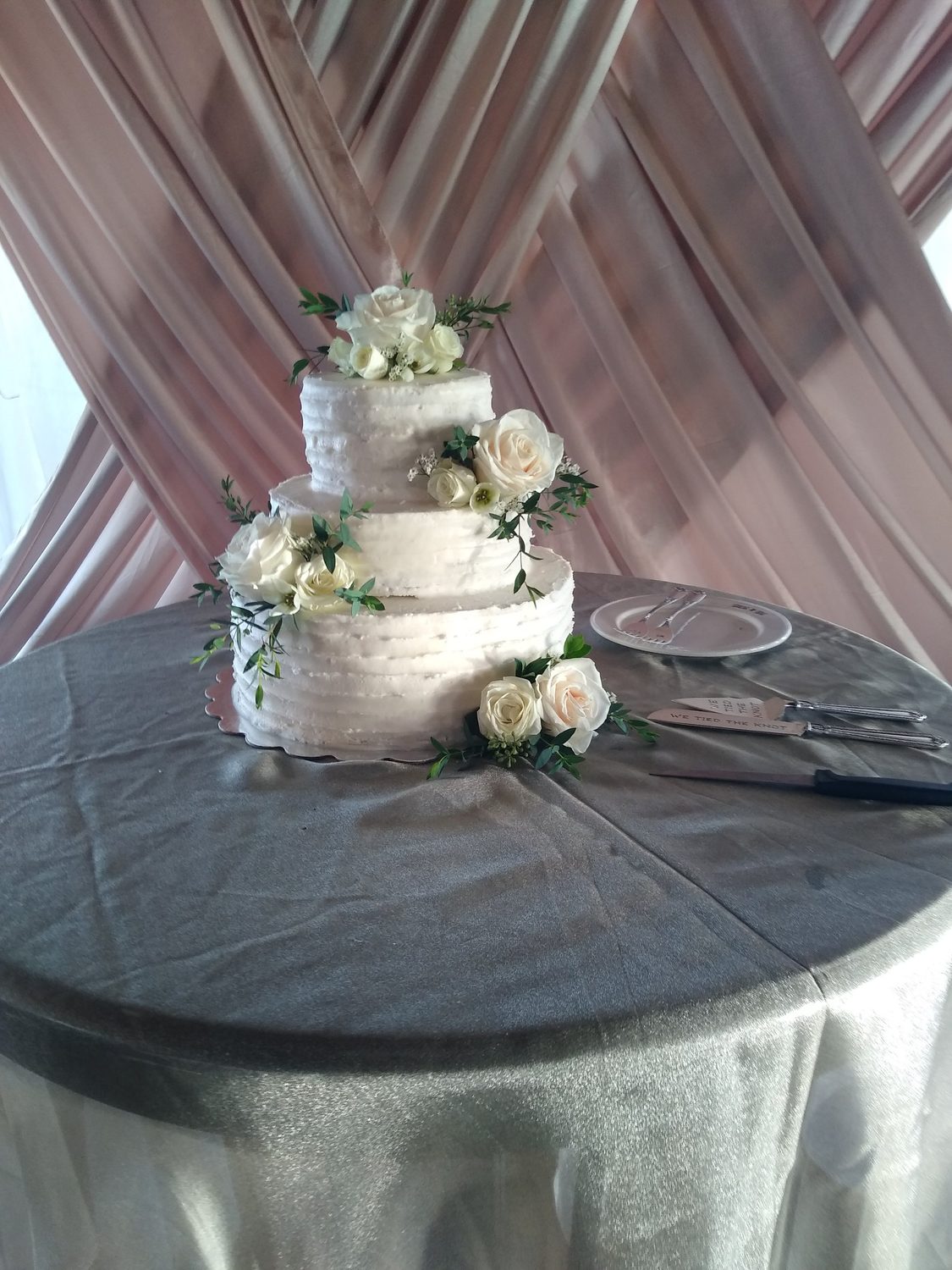 White garden roses and Italian ruscus tucked into a three-tier cake