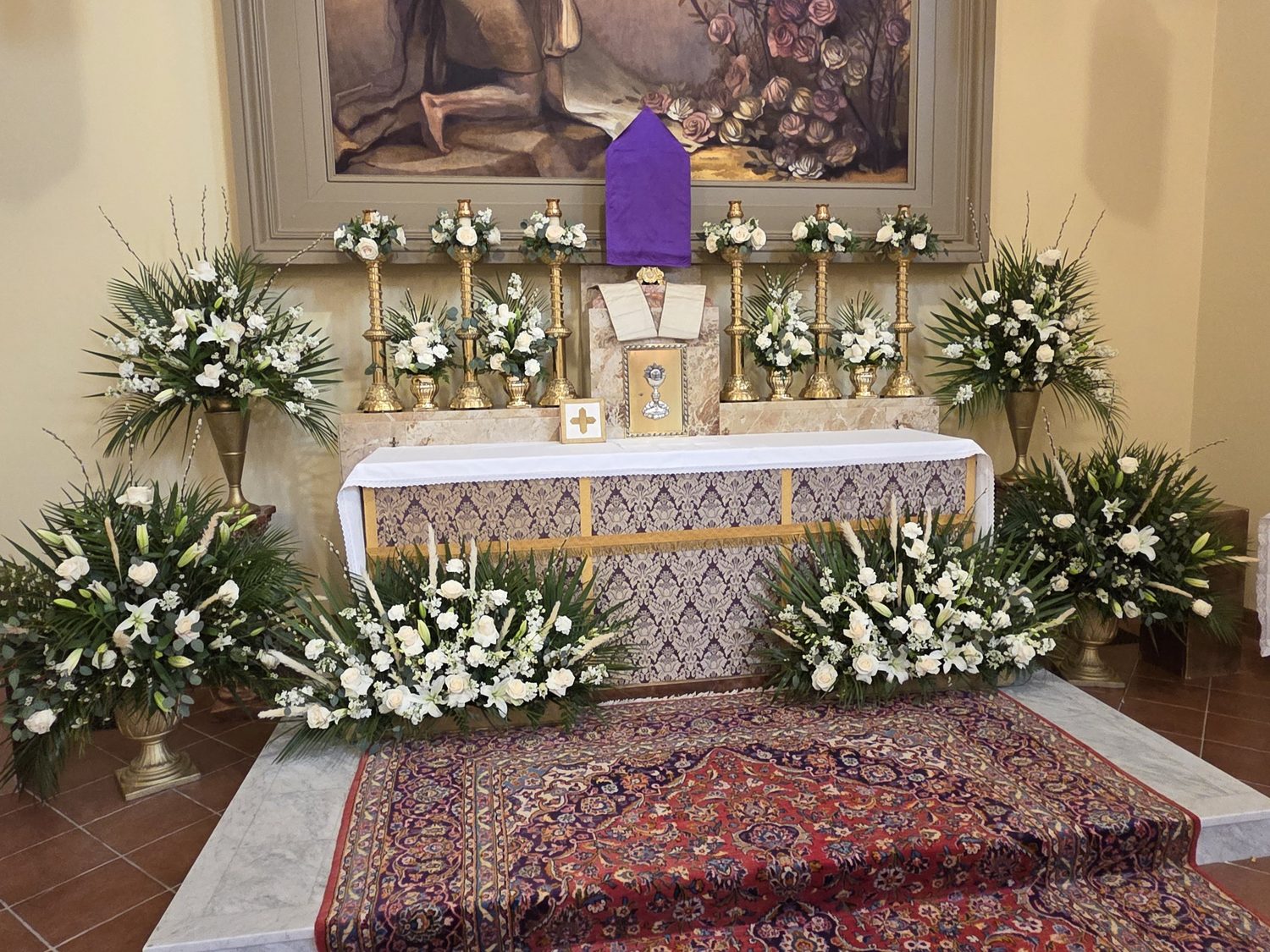 White roses, lilies and palms filling the sanctuary, with roses crowning every candlestick